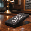 Unbranded glitter Last Orders phone case on a dark pub bar (product image, invented unbranded)