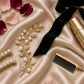 Golden Hour Occasion Updo – Pearl hair pins, gold leaf hair vine, black velvet ribbon, gold comb and hairspray on champagne silk with roses (product image, invented unbranded)