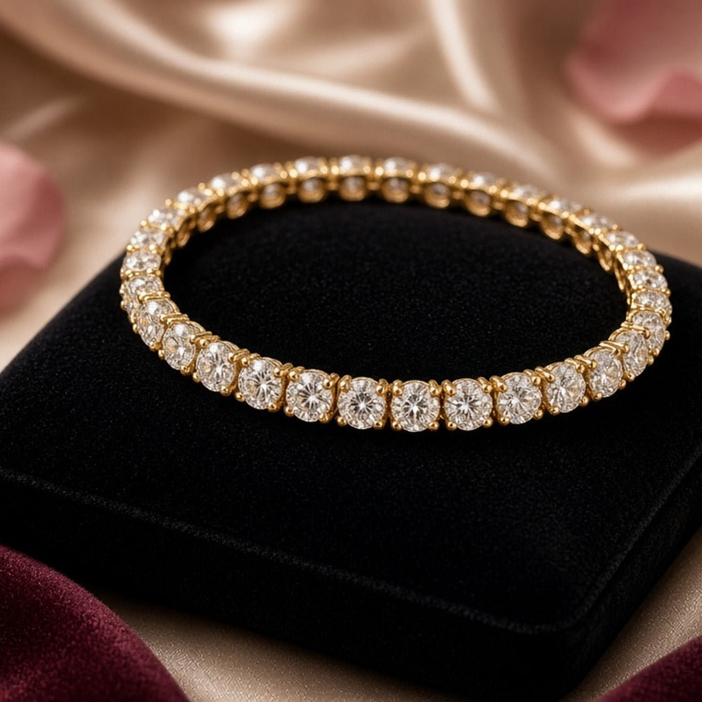 Empress Gold Tennis Bracelet – Gold tennis bracelet with white stones coiled on a black velvet cushion with champagne silk and rose petals (product image, invented unbranded)