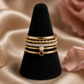 Five-Stack Gold Rings Set – Five slim gold stacking rings on a black velvet ring cone with champagne silk and rose petals (product image, invented unbranded)