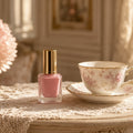 Blush Petal Sheer Lacquer – blush-pink nail polish beside a floral teacup on a lace table