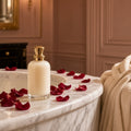 Crimson Rose Bath Oil Ritual – cream bath oil bottle with gold cap on marble bath rim with red rose petals