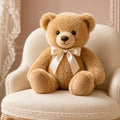 Honey Velvet Heirloom Teddy – honey teddy bear with cream satin bow on cream chair