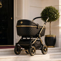 Obsidian Empress Flagship Pram – black quilted pram with gold frame on townhouse steps by a topiary