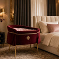Rouge Velvet Bedside Crib – burgundy velvet bedside bassinet with gold trim beside cream bed